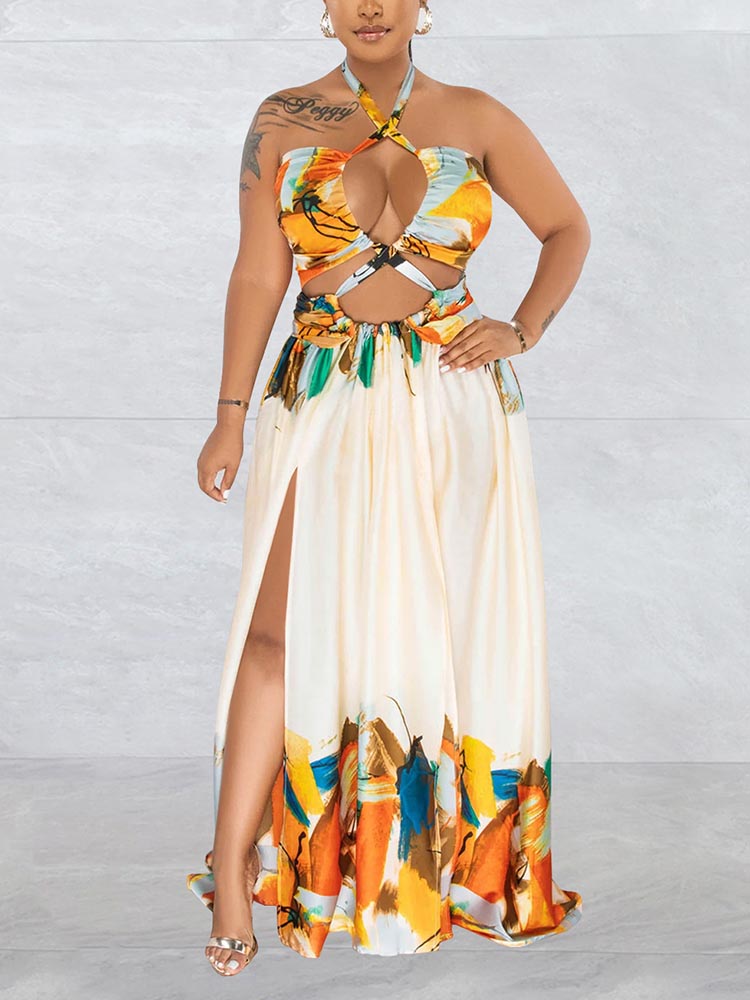 woman wearing a cream colored abstract print halter neck maxi dress with cut-out details and a high slit showing her leg