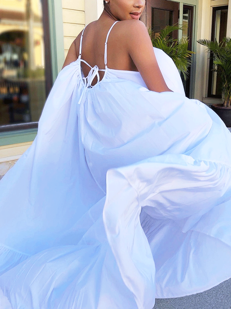 Close-up back view of a woman in a white maxi dress, showing the tie detail.