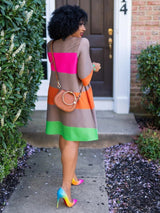 A woman's back is shown as she walks away wearing a striped A-line dress and ombre heels.