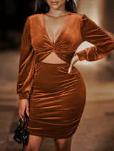 Woman wearing a rust-colored velvet bodycon dress with a v-neck, twist front detail, cut-out waist, ruched skirt, and long sleeves.