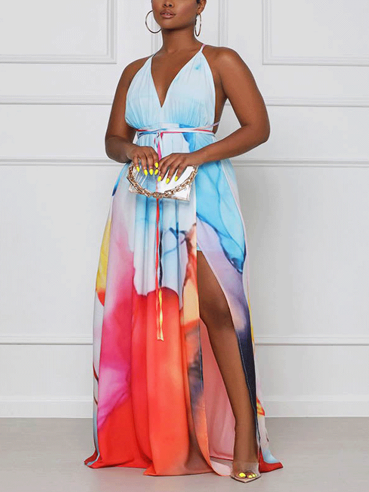 Woman wearing a flowing, sleeveless maxi dress with a vibrant abstract print and a high slit.