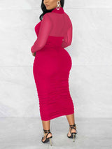 Back view of a woman in a magenta ruched sheath dress with a criss-cross neckline and sheer long sleeves.