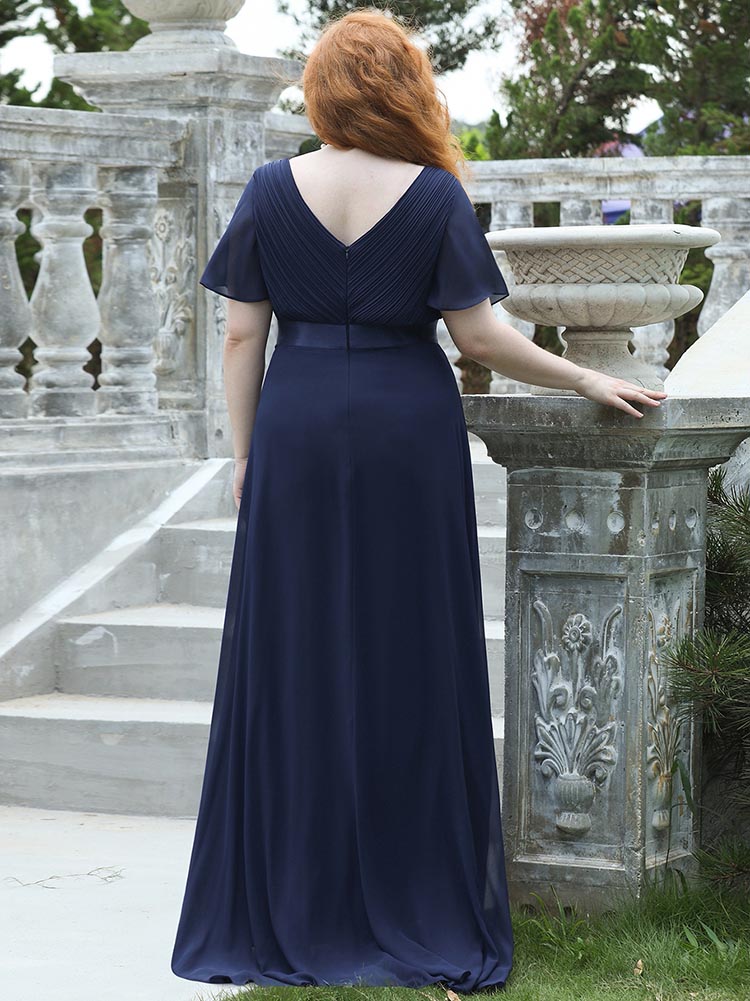 Back view of a woman in a navy blue formal gown, showcasing the V-back and flowing skirt.