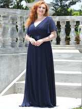 Full-length view of a woman wearing a navy blue formal dress with a pleated bodice and A-line skirt.