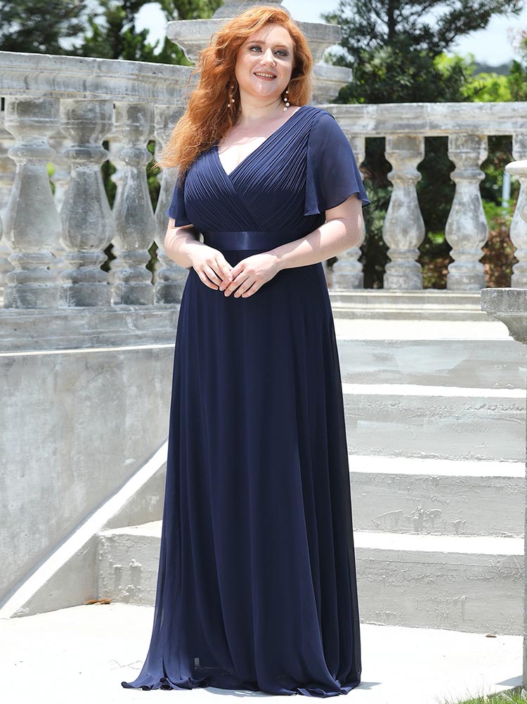 Full-length view of a woman wearing a navy blue formal dress with a pleated bodice and A-line skirt.