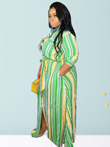 Woman wearing a green, yellow, and white striped maxi dress with a belted waist and side slits, holding a yellow purse.