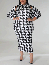 Plus size model wearing a black and white houndstooth print mock neck midi dress and a matching jacket with cut-out shoulders