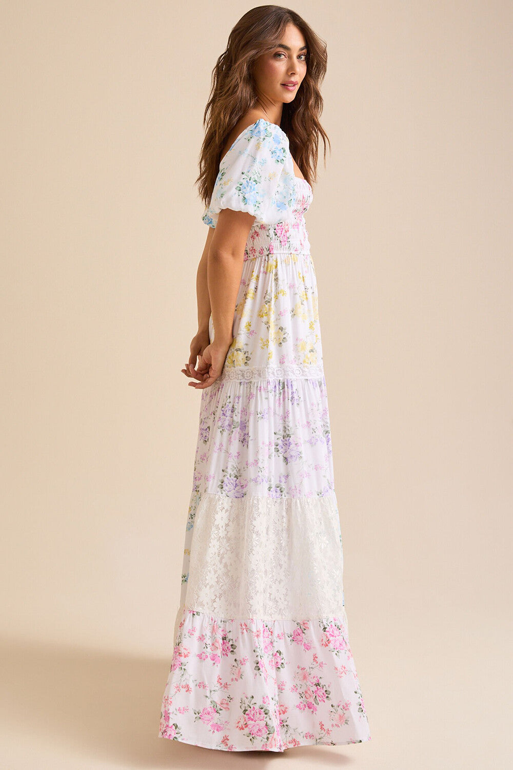 Side view of a woman wearing a white floral print maxi dress with puff sleeves and a square neckline.