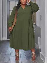 Plus-size model wearing a green tiered midi dress with voluminous sleeves and long braided hair.