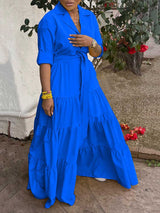 Woman wearing a blue tiered maxi dress with a collared neckline and a belted waist.