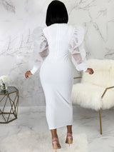 Back view of a woman in a white midi dress with sheer puff sleeves