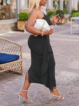 Side view of a woman in a black one-shoulder ruched midi dress with an asymmetrical hem.
