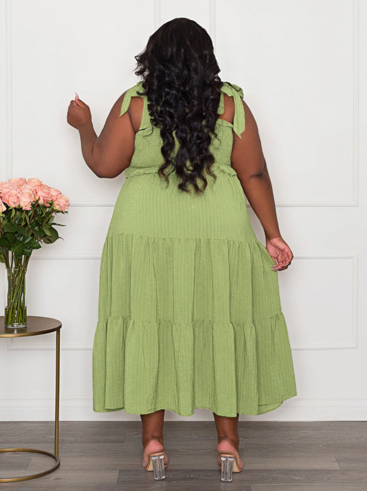 Back view of a plus-size woman wearing a lime green tiered maxi dress with tie shoulder straps and a smocked bodice.