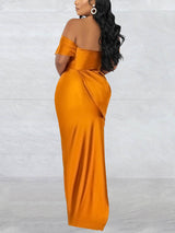 Back view of a woman in a floor-length golden yellow off-the-shoulder dress with draped detailing