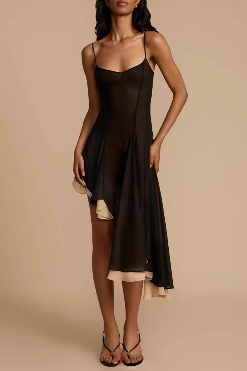 Woman wearing a black and cream asymmetrical chiffon dress with spaghetti straps, standing facing forward.