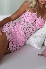 Woman in a pink lace mini dress with cut-out details, lying on a white couch.
