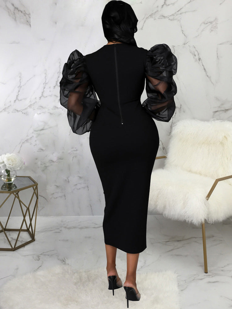 Back view of a woman in a black midi dress with sheer puff sleeves