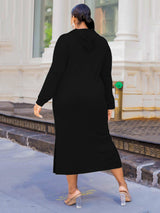 Back view of a woman wearing a black midi hooded dress with side slits and pockets.