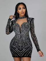 Woman wearing a black long-sleeved mini dress adorned with sparkling rhinestones. The dress features a high neckline with a cutout and a deep V-neckline, with structured shoulders.