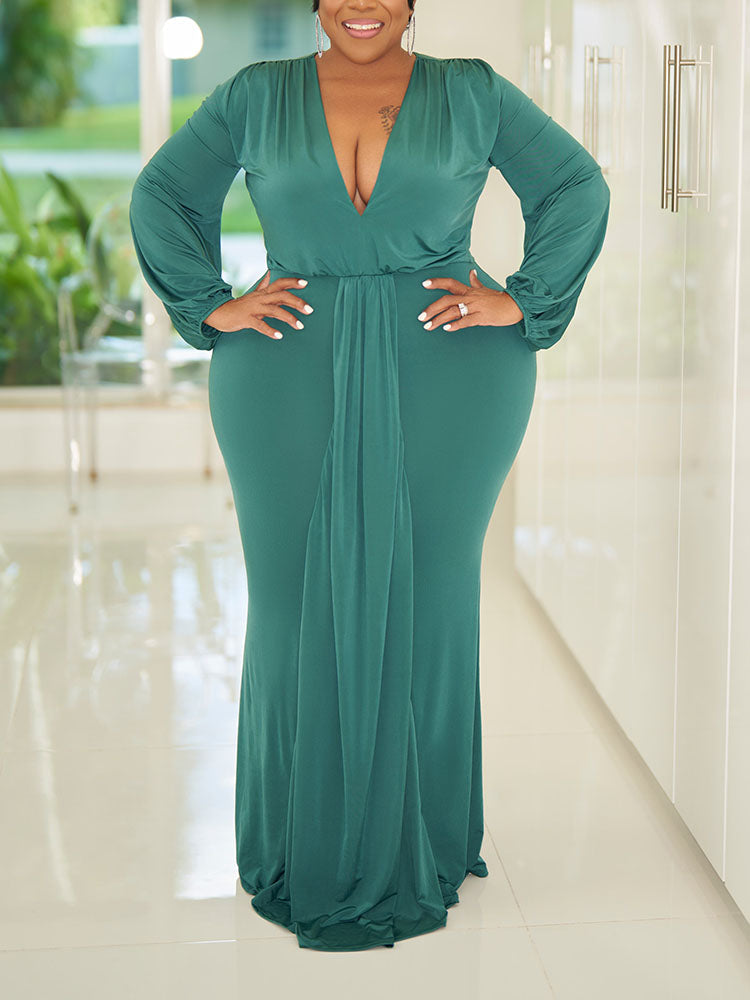 Woman wearing a teal, floor-length, long-sleeved gown with a V-neckline and draped skirt