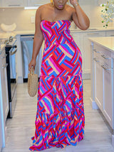 Woman in a red, pink, and blue geometric print strapless maxi dress