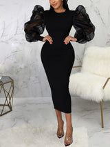 Woman wearing a black midi dress with sheer puff sleeves