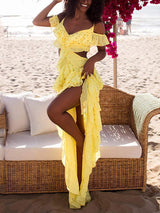 Woman wearing a yellow polka dot maxi dress with ruffles and cut-outs on the beach