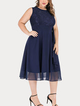 Woman wearing a navy blue lace and chiffon A-line knee-length dress with a round neckline and sleeveless design