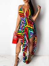 Woman wearing a multicolored striped halter dress with an asymmetrical hemline and a plunging neckline.