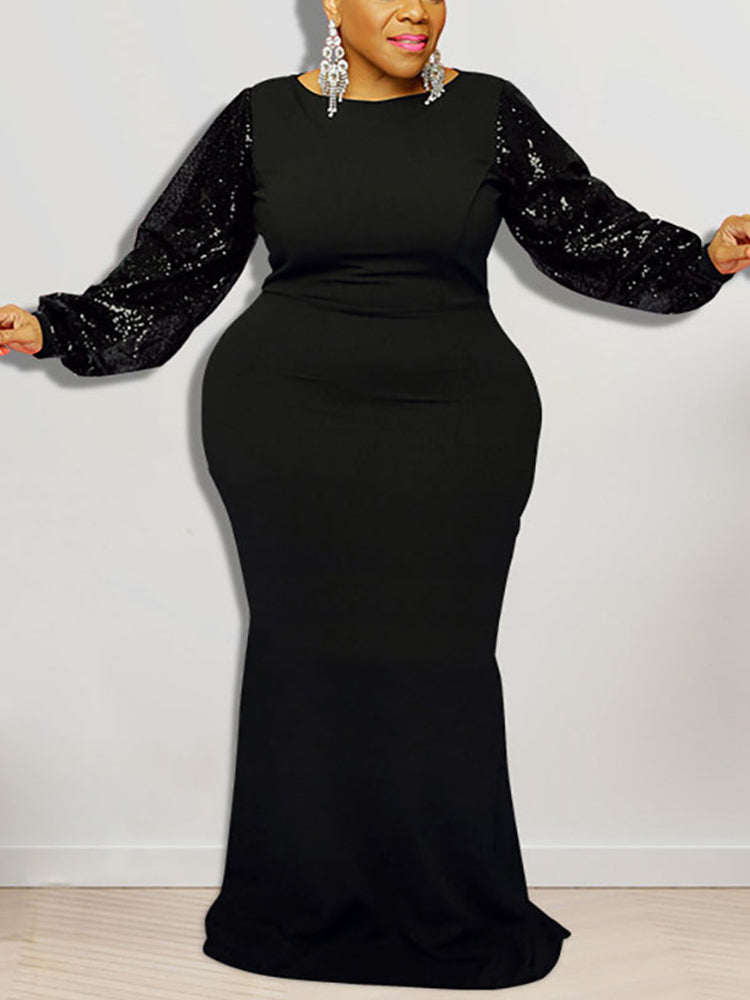 Woman wearing a black floor-length dress with sequined long puff sleeves and a round neckline.