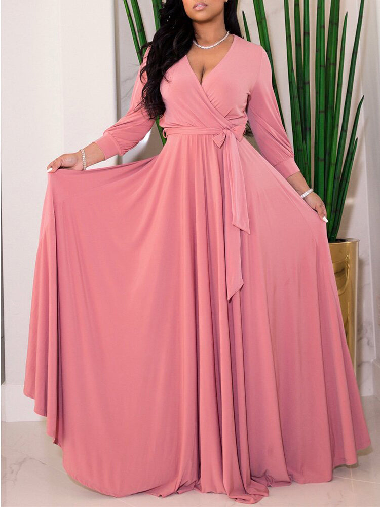 Woman wearing a dusty rose maxi dress with a wrap neckline and long sleeves.