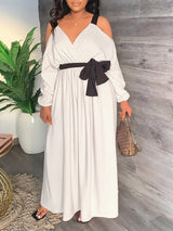 Woman wearing a long, off-the-shoulder white dress with a black tie-waist belt.