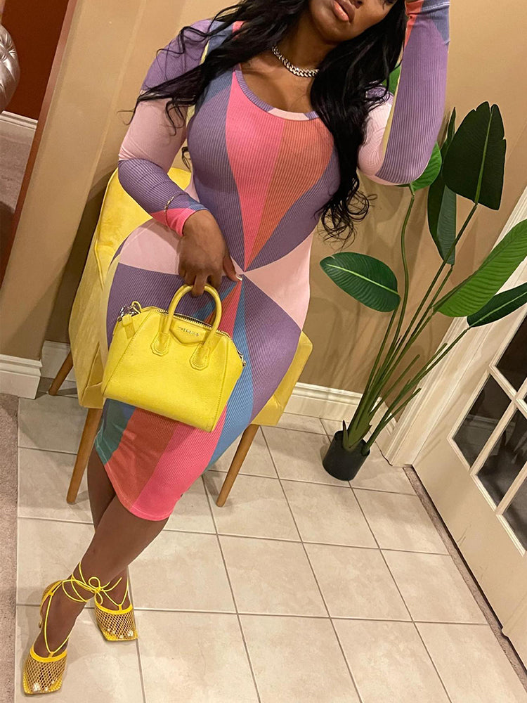Woman wearing a long-sleeved, midi-length bodycon dress with a colorful geometric print, paired with yellow strappy heels and a yellow handbag.
