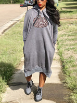 Woman wearing a grey hooded midi dress with a pumpkin graphic print and leopard pattern, standing outdoors.