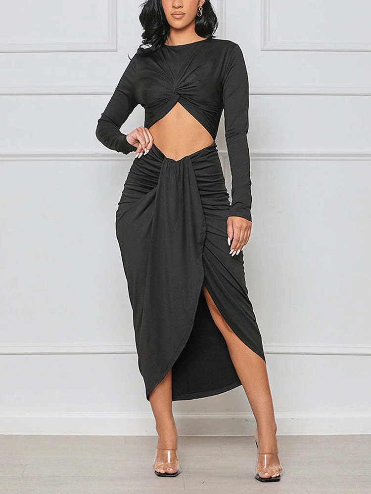 Woman wearing a black long-sleeve crop top with a twist-front detail and a matching high-slit ruched midi skirt.