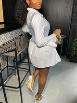 Side view of a woman in a white collared shirt dress with a denim vest overlay and white heels