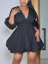 Woman in a black puff sleeve mini dress with a V-neckline and bubble hem.
