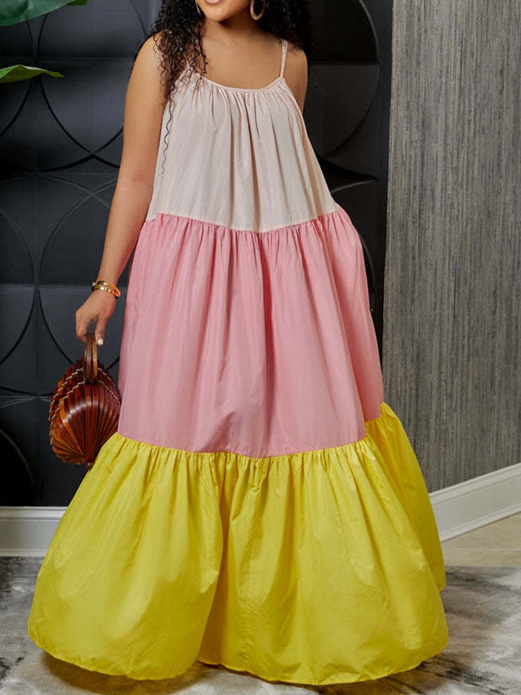 Woman in a colorful tiered maxi dress with spaghetti straps, holding a woven handbag. The dress features color blocking in light pink, pastel pink, and yellow.