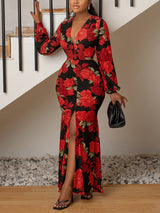 Woman wearing a long black dress with a red rose floral print, V-neck, long sleeves, and a high slit.