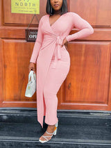 woman wearing a long-sleeved pink wrap dress with a tie waist and side slit