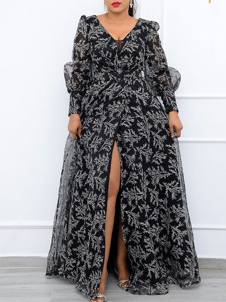 Woman wearing a long black and white floral print gown with a high slit, showcasing sheer puff sleeves and a V-neckline.