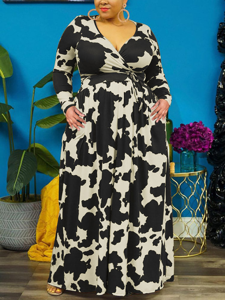 Woman with hands in pockets wearing a black and white cow print maxi dress.