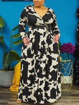 Woman with hands in pockets wearing a black and white cow print maxi dress.