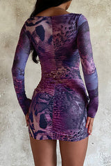 back view of a woman wearing a purple long-sleeved mini dress with a square neckline and ruffled hem