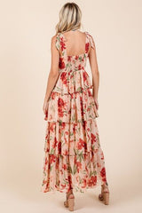 Back view of a woman wearing a blush pink floral print tiered maxi dress