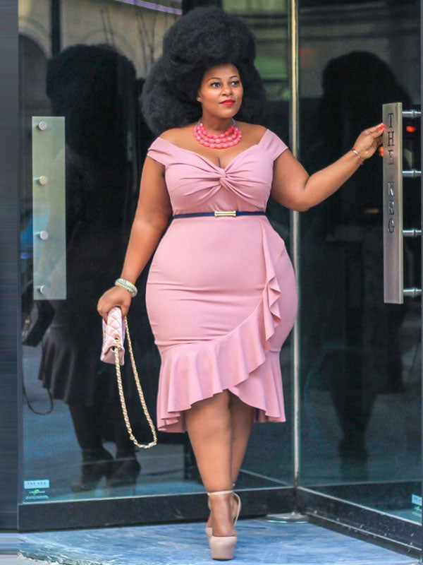 Woman with a large afro hairstyle posing in a pink off-the-shoulder dress with ruffle detail.
