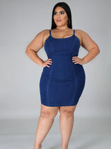Woman posing in a denim sheath dress with hands on hips.
