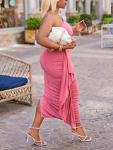 Side view of a woman in a pink one-shoulder ruched midi dress with an asymmetrical hem.