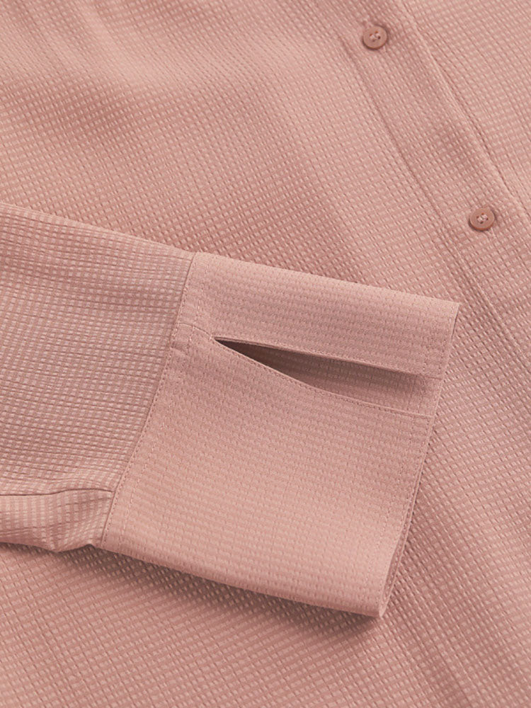 Close-up of the cuff and textured fabric of a pink collared shirt dress.