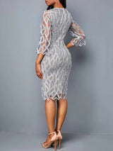 Back view of a plus-size model wearing a light grey lace sheath dress.